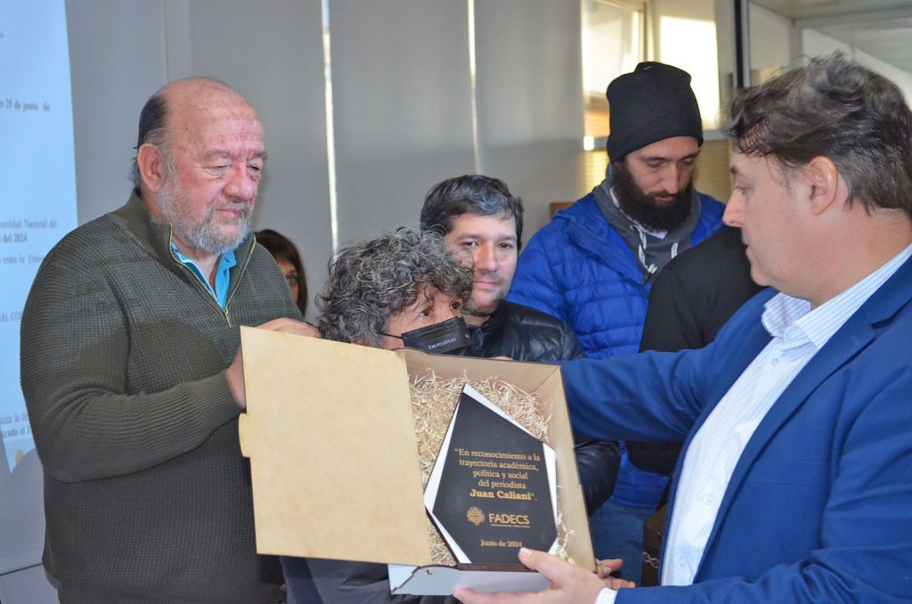 LA FADECS-UNCO HIZO ENTREGA DE DIPLOMA Y PLACA A LA FAMILIA DE JUAN CALIANI

El Consejo Directivo de la FADECS hizo entrega de un diploma en reconocimiento a la trayectoria formativa de Juan Caliani, durante un acto realizado el martes 25 de junio en el Consejo Superior de la UNCo. Además del diploma, se entregó a la familia de Juan una placa con la leyenda “En reconocimiento a la trayectoria académica, política y social del periodista Juan Caliani” (Resolución 0114/2024).

El diploma de Licenciado en Comunicación Social con orientación en Periodismo a favor de Juan Caliani, se fundamenta "en la intención de reconocer simbólicamente la trayectoria académica de Juan, quien fue estudiante de nuestra facultad y en el año 2024 había retomado la cursada de sus últimas materias para obtener el título de grado".

La placa es un reconocimiento por haber sido "un integrante sumamente valioso de nuestra comunidad universitaria, no solo por su trayecto como estudiante, sino también por su compromiso militante por la universidad pública y por una sociedad de iguales y más justa. Además, fue miembro del Consejo Directivo y del Consejo Superior por parte del claustro estudiantil en varias ocasiones".

Cabe recordar que "la vida de Juan finalizó de manera abrupta el 2 de abril del 2024 y nos dejó con una profunda herida, difícil de sanar, tanto a la comunidad académica de la FADECS como a la de la UNCo. Ha recibido numerosos reconocimientos como también el apoyo al pedido de justicia para el esclarecimiento de su homicidio".